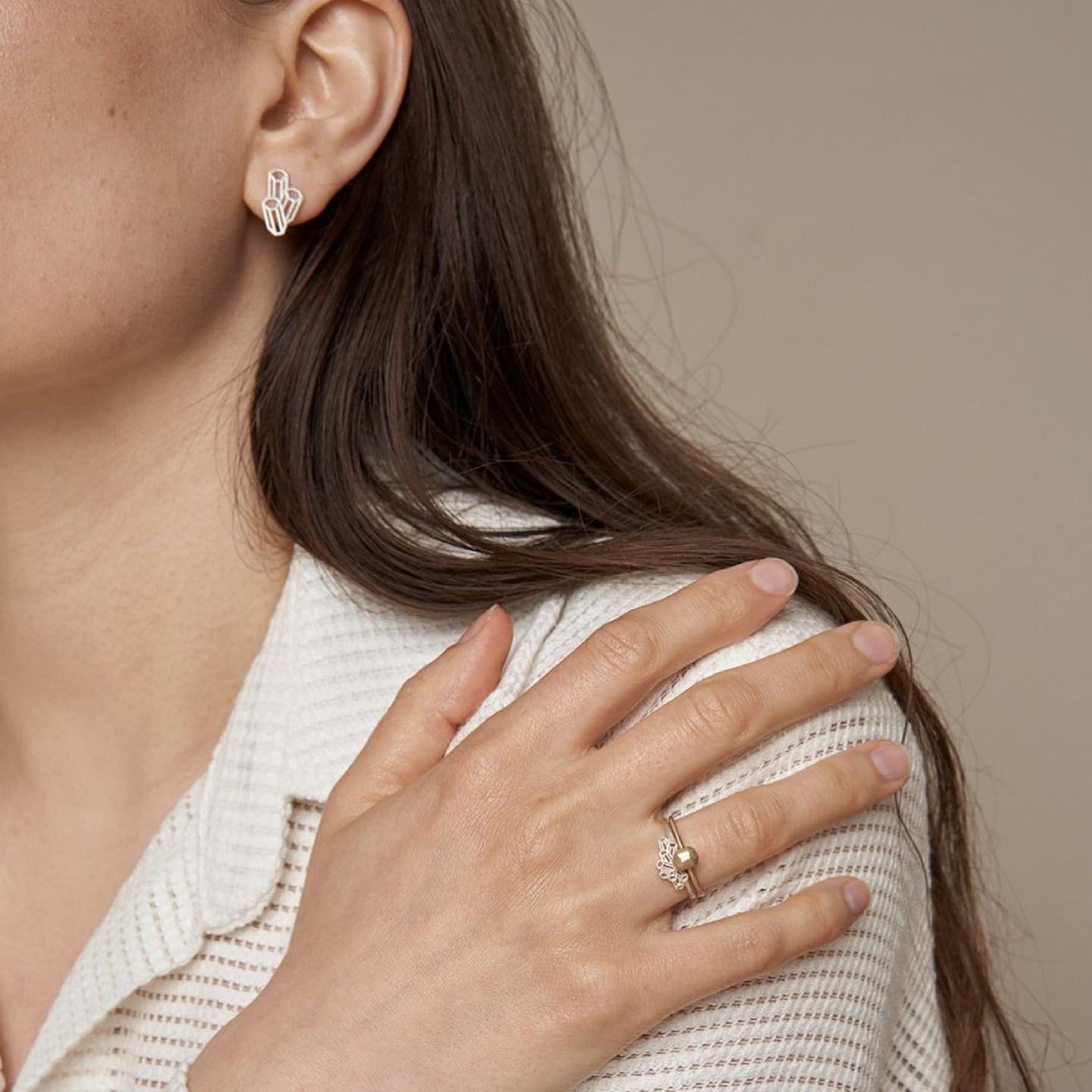 Model wearing silver geometric cluster stud earrings and a ring.