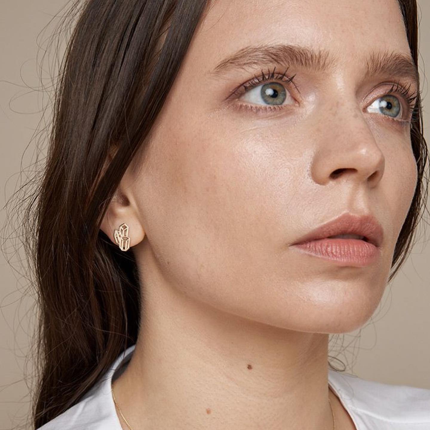 Close-up portrait showing geometric silver stud earrings.