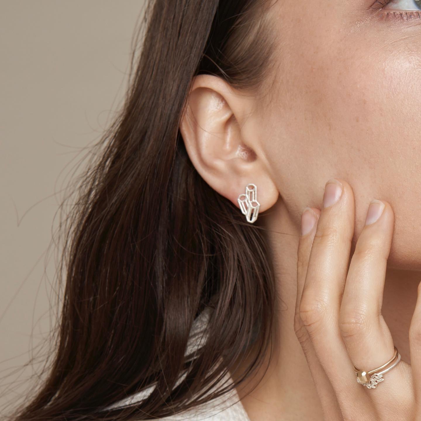Close crop of geometric silver stud earring and matching ring.