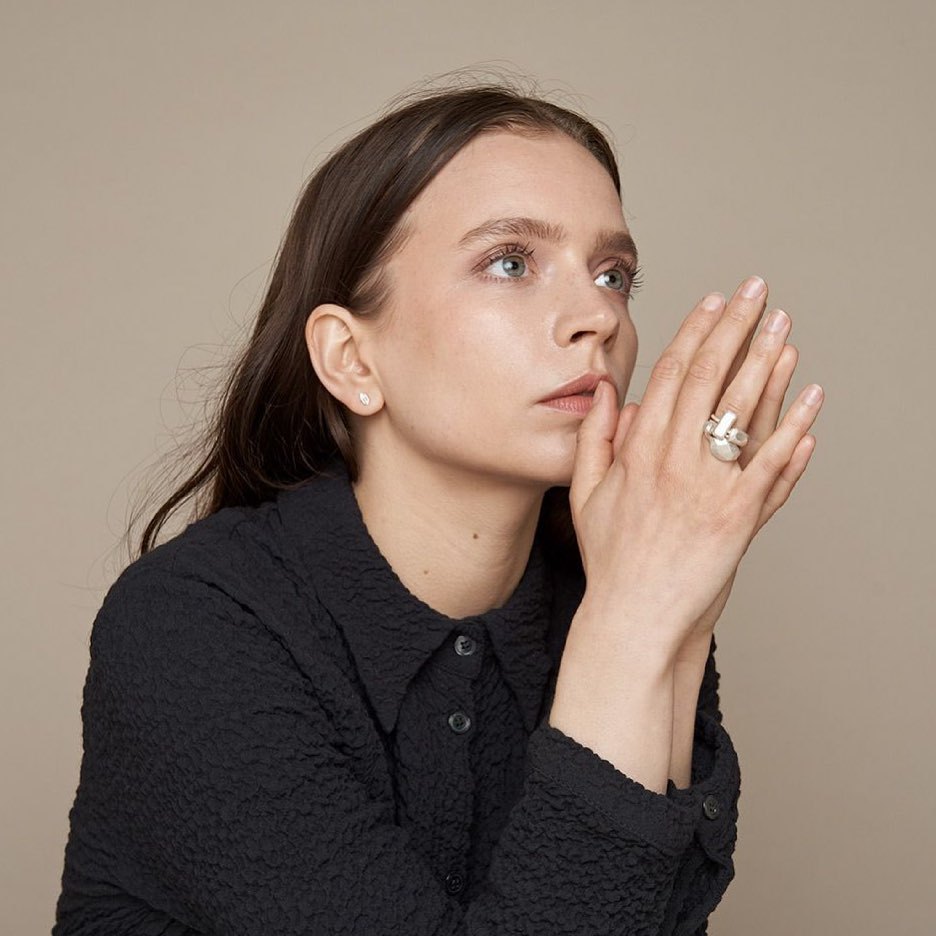 Model wearing a geometric silver ring with small matching studs.