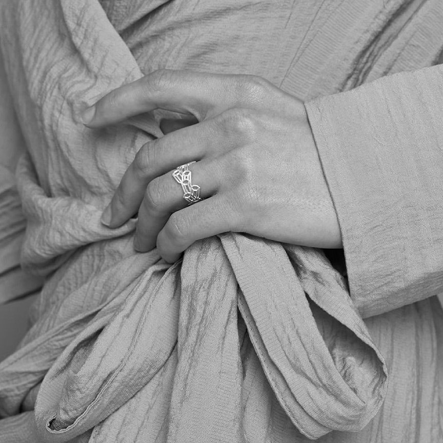 Black and white image of a hand wearing a geometric facet ring.