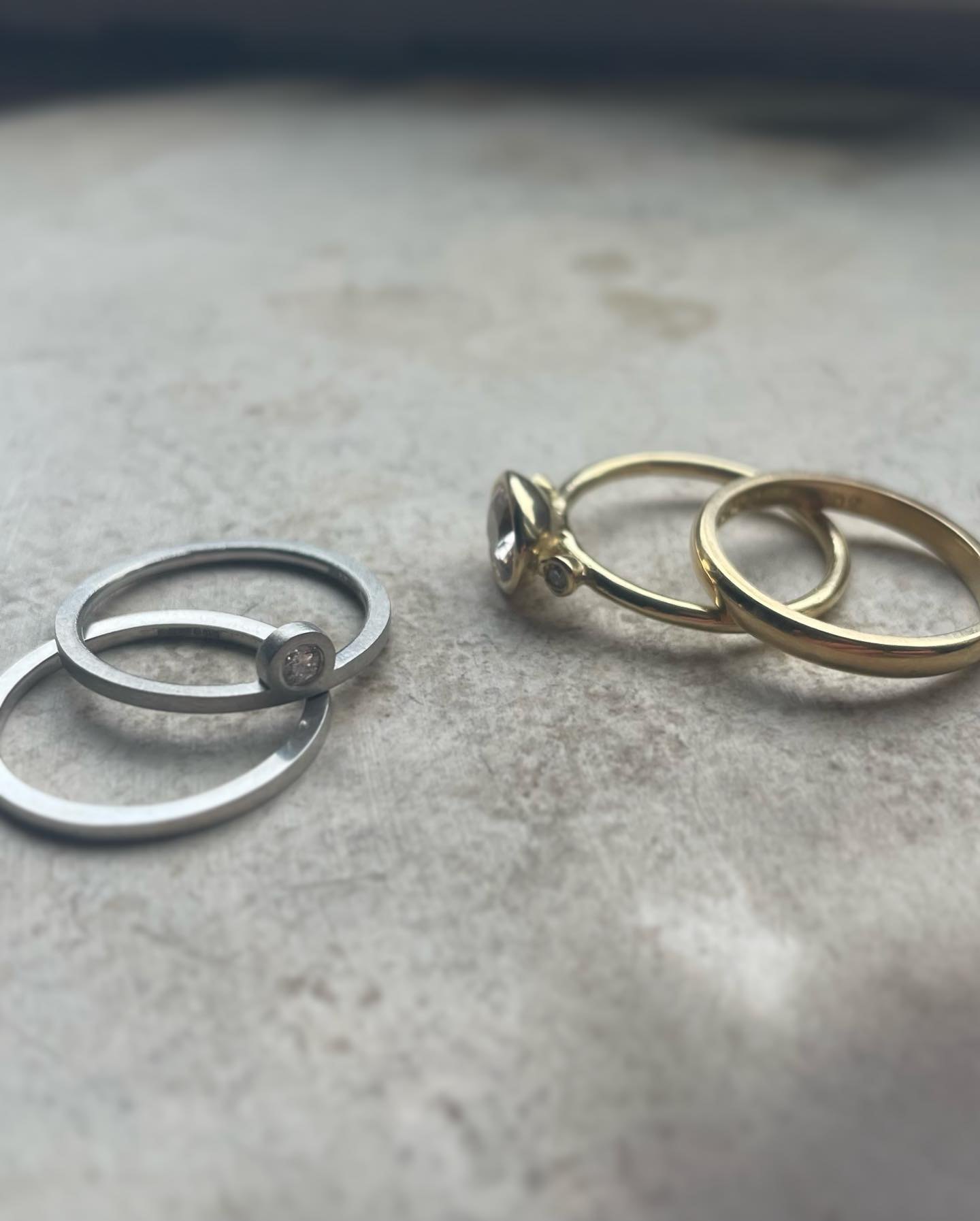 Group of silver and gold stone-set rings on a textured surface.
