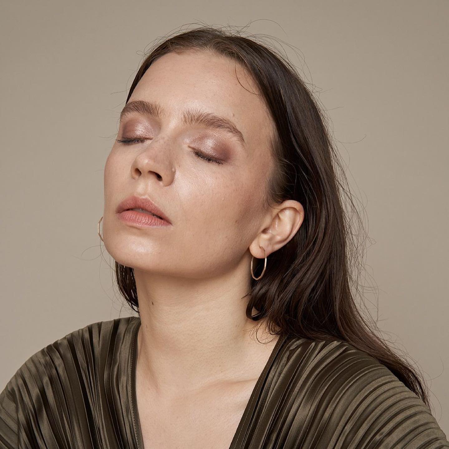 Model wearing slim irregular oval hoop earrings.